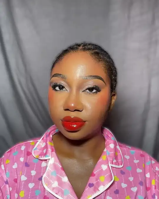Bold red lip and pink blush on a woman in heart-print pyjamas